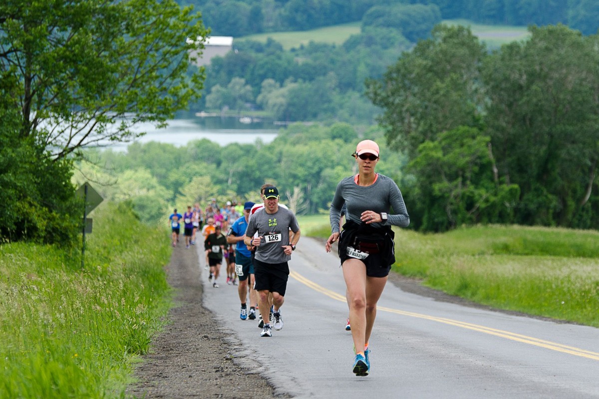 people running uphill with Otsego Lake in the background