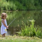 Young girl fishing by pond