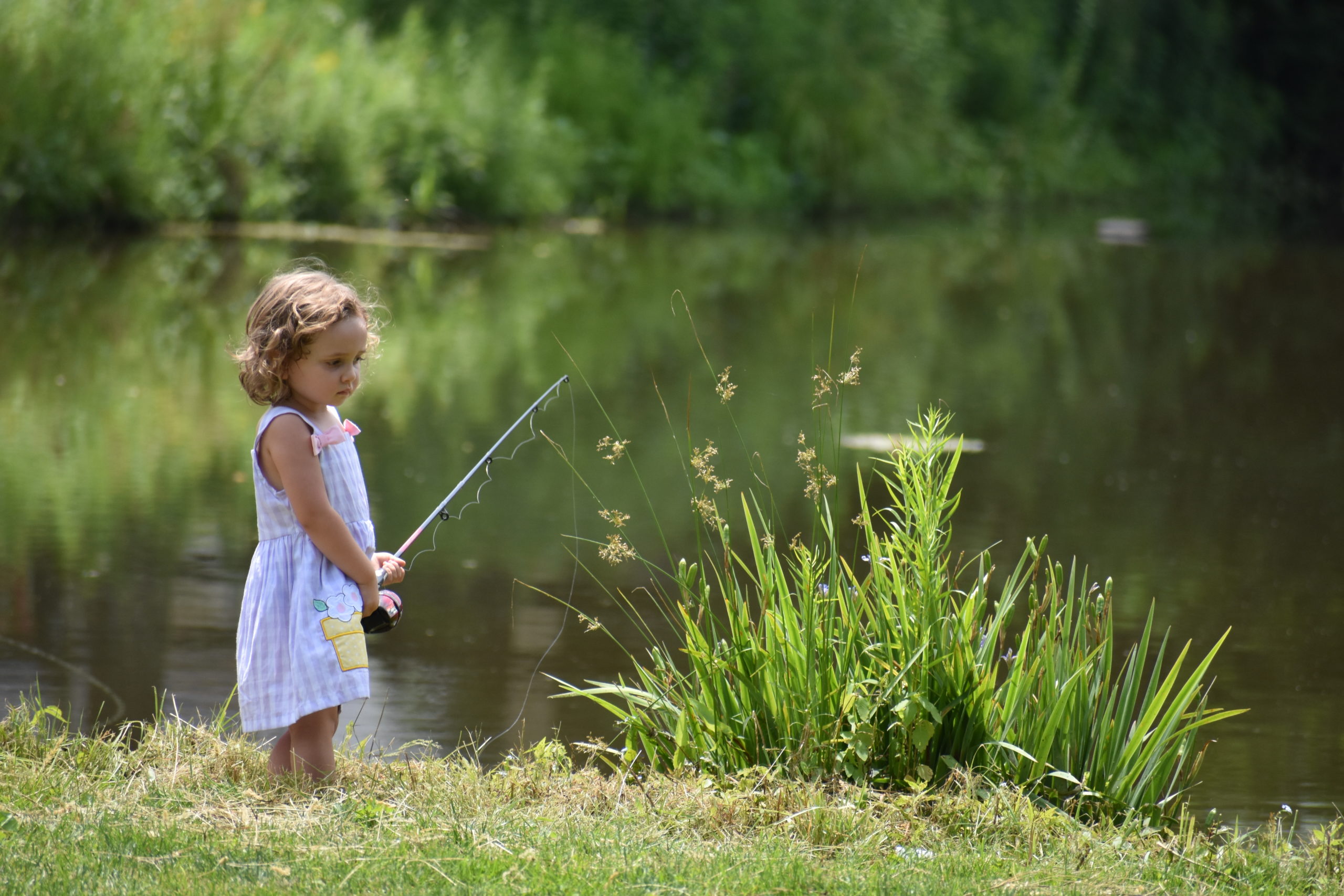 Young girl fishing by pond