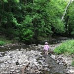a young girl walks in a shallow creek