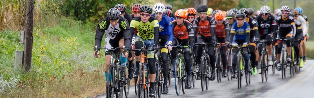 helmeted cyclists ride along a country road