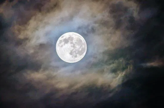 A full moon surrounded by clouds