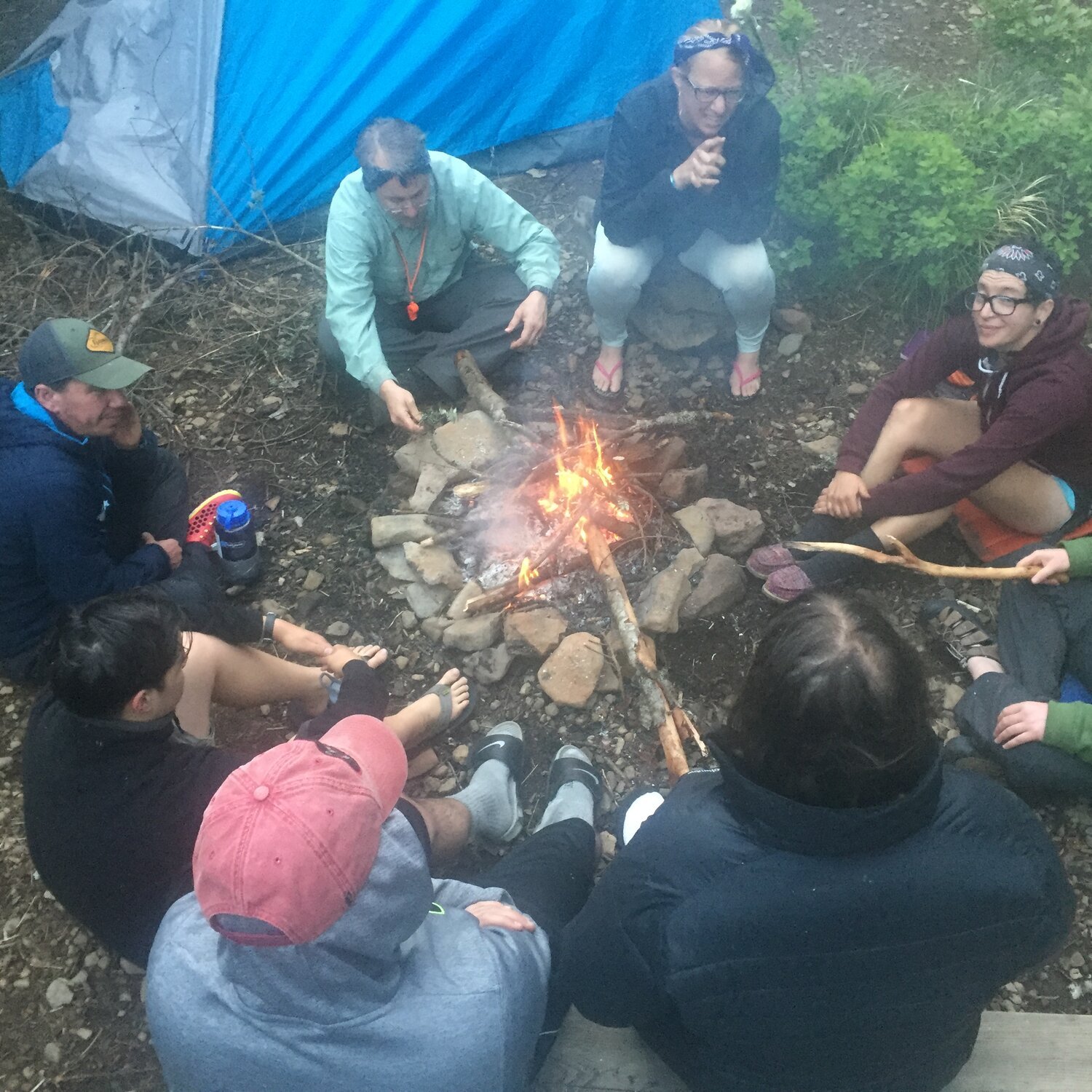 people camping sitting around a fire