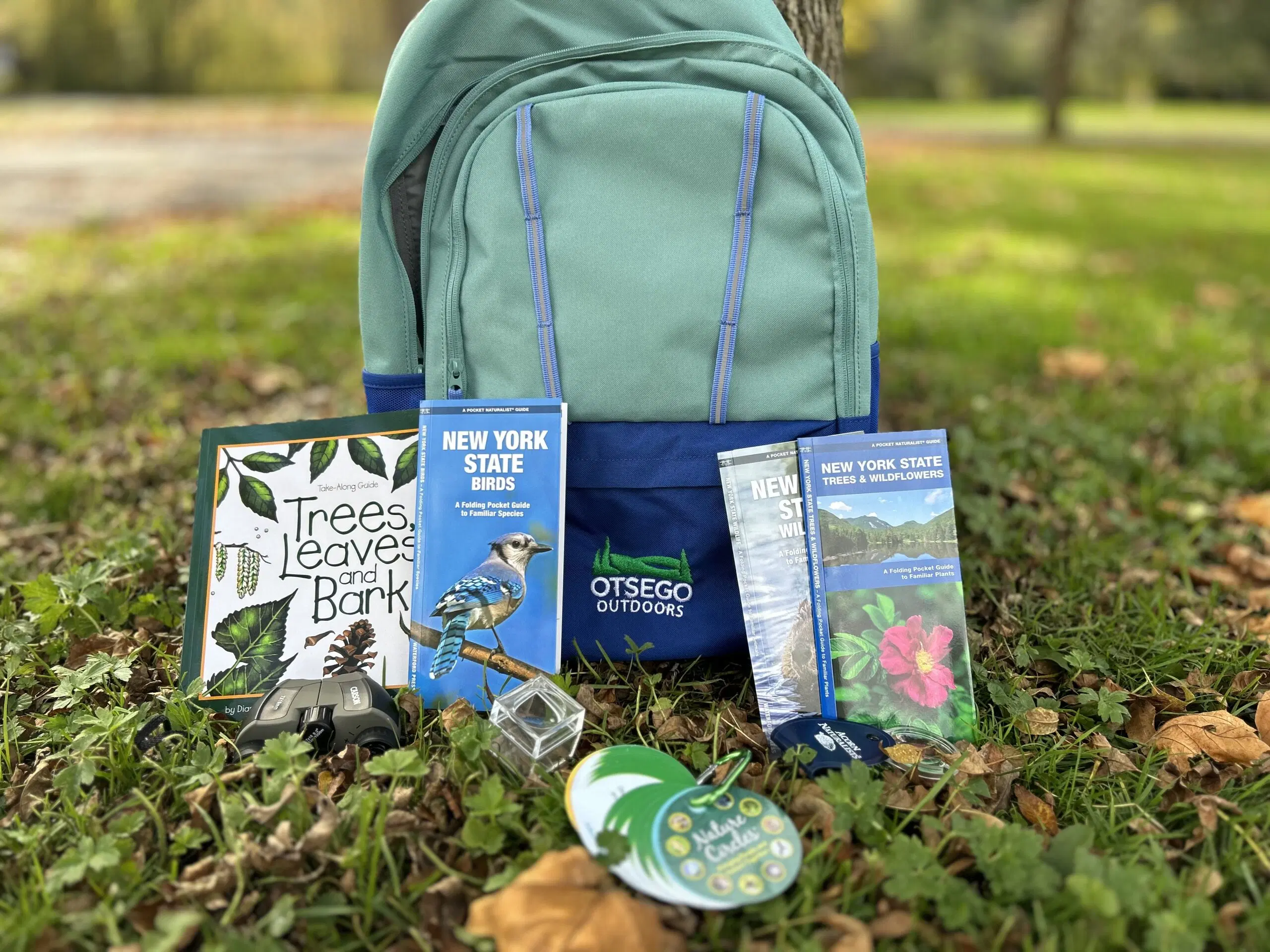 An Otsego Outdoors backpack with guidebooks, a picture book, and outdoor equipment
