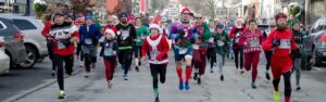 People running in a street, some with Santa hats