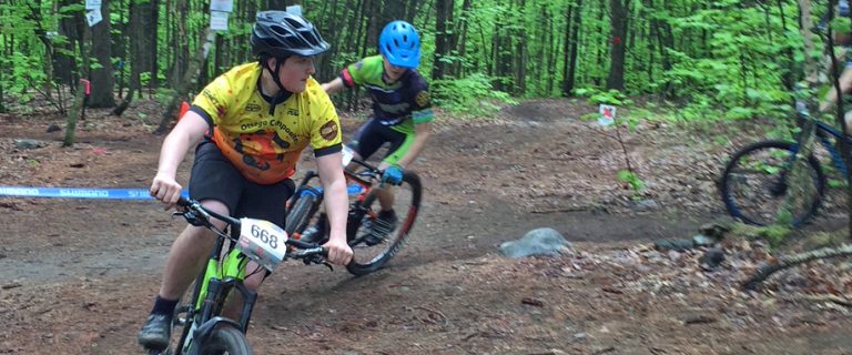 Two teenagers mountain biking on a wooded trail