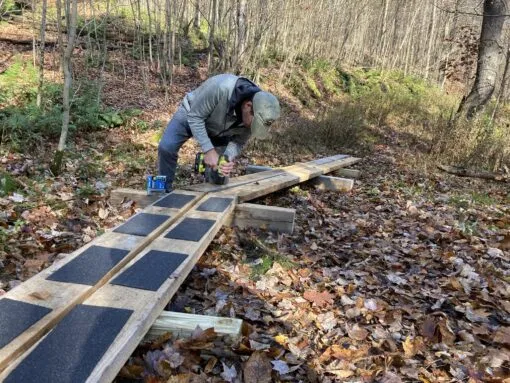 a volunteer is working on an elevated wooden pathway